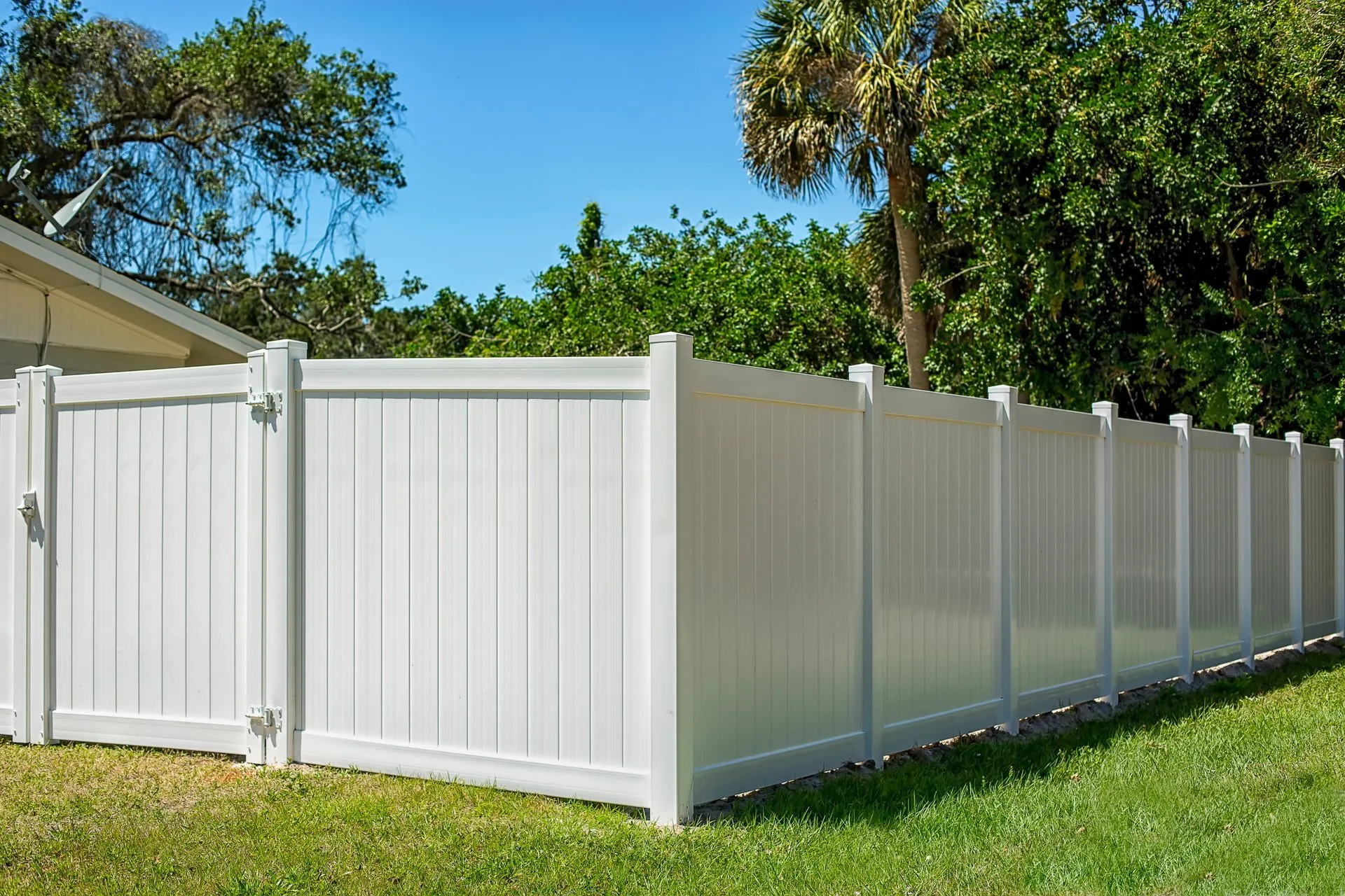 White vinyl fence with a matching gate installed at a residential property entrance