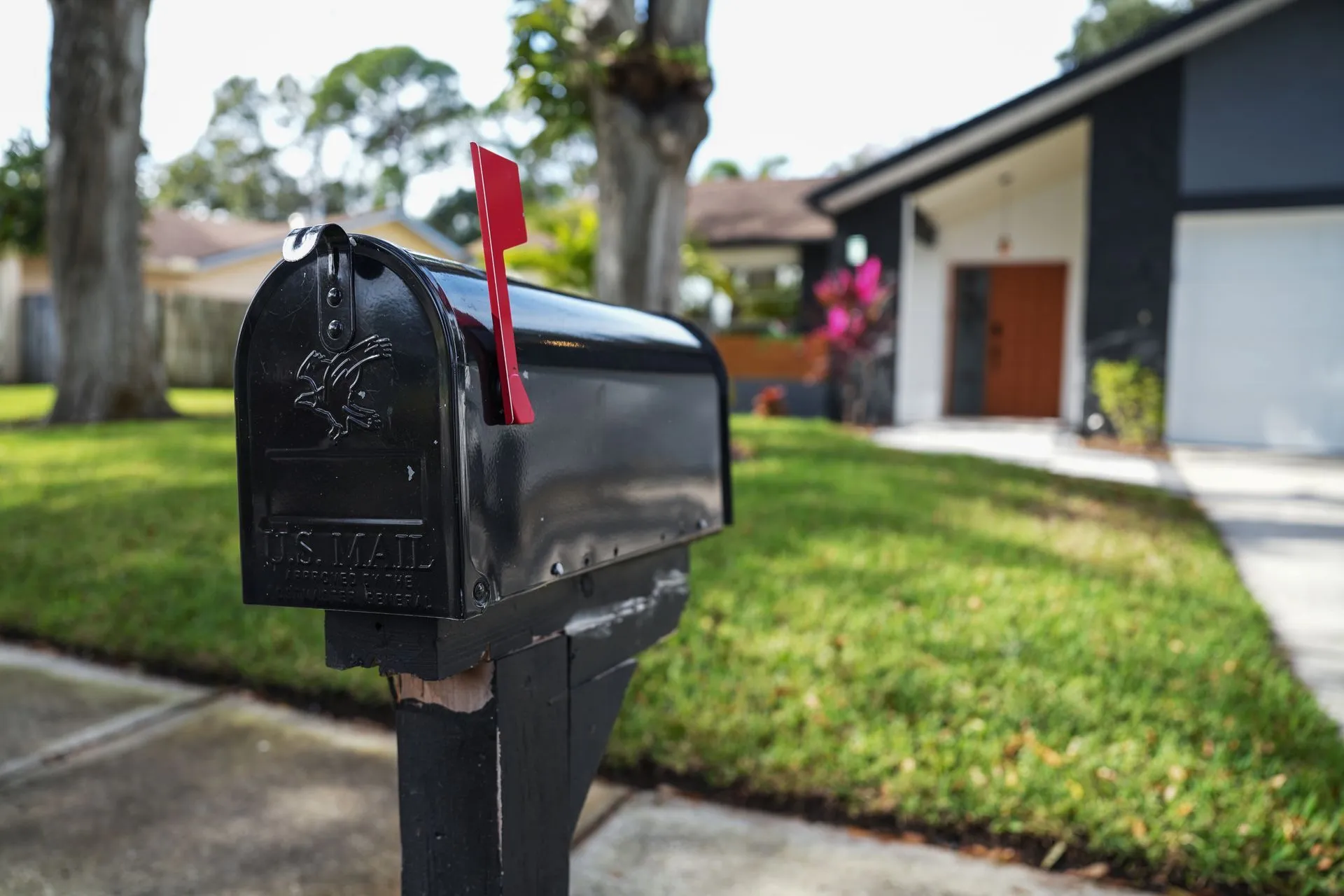 Black mailbox mounted on a secure post at the end of a residential driveway